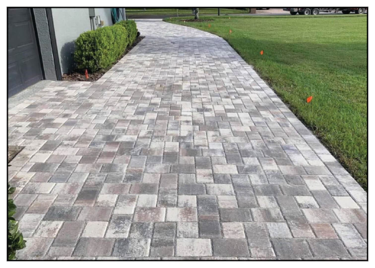 A picture of a driveway with green grass on the side