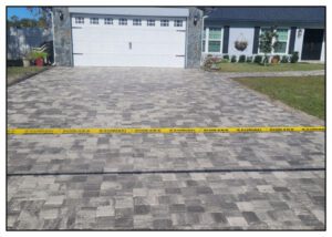 A paver driveway with a warning tape on it.