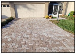 A driveway with brick pavers in front of a house.