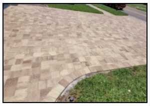 A brick driveway with green grass.