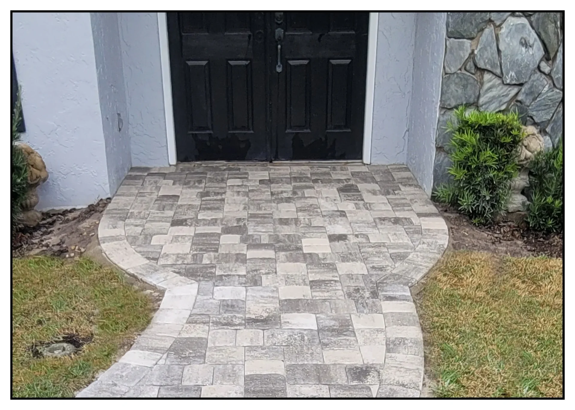 Brick path leading to black double doors.