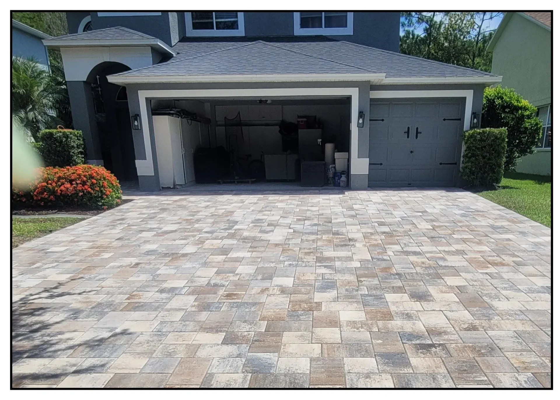 Driveway with open garage and flowers nearby.